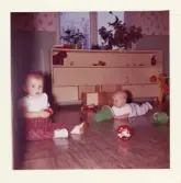 Fotografi på två barn, Tex och Thorbjörn, som leker på golvet.