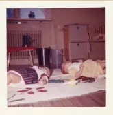 Fotografi på två små spädbarn som ligger på en filt på golvet, troligen i Lilla Källbäck.