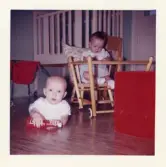 Fotografi på Thorbjörn och Annika, där den ena sitter i en barnstol och en ligger på golvet.