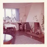 Fotografi på vardagsrummet med öppen spis, bord och stolar vid barnhemmet Lilla Källbäck, påsken 1962.