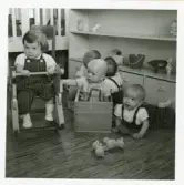 Fotografi på Lars, Mikael och Susanna som leker på golvet vid barnhemmet Lilla Källbäck, 1963.