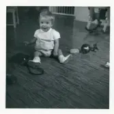 Fotografi på ett barn som sitter på golvet och leker vid barnhemmet Lilla Källbäck.