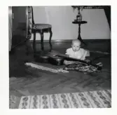 Fotografi på Susanne liggandes på magen på golvet framför en gitarr.