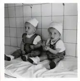 Fotografi på Urban och Anders med hängselbyxor sittandes på en bänk, troligen i Lilla Källbäck.