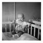 Fotografi på Thorbjörn sittandes i en spjälsäng i Lilla Källbäck.