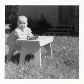 Fotografi på Eva som står i gräset och håller sig i en pall vid Lilla Källbäck.