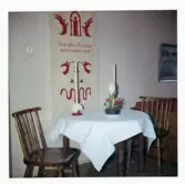 Fotografi på ett rum med bord och två stolar samt en väggbonad, julen 1963 på Lilla Källbäck.