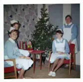Fotografi på barnsköterskor sittande vid julgranen, julen 1963 på Lilla Källbäck.