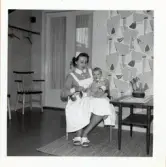 Fotografi på en barnsköterska som sitter med ett barn i knät på Lilla Källbäck.