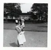 Fotografi på en barnsköterska som bär på Sven-Olof vid Lilla Källbäck.