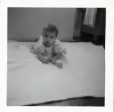 Fotografi på Marina liggandes på en filt med en leksak framför sig i Lilla Källbäck.