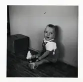 Fotografi på Janne sittande på golvet med leksak i Lilla Källbäck.