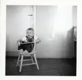 Fotografi på Peter sittande på en barnstol i Lilla Källbäck.