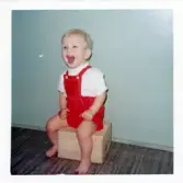 Fotografi på en glad Sten-Åke som sitter på en trälåda i Lilla Källbäck.