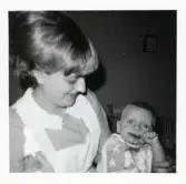 Fotografi på en barnsköterska med ett barn som äter själv i famnen, i Lilla Källbäck.