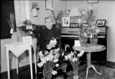 Kvinna i hemmet omgiven av blommor, Upplands-Tuna, Tuna socken, Uppland, 1952