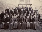 Gruppbild med unga flickor och pojkar, konfirmander eller skolklass. Fotograferat vid Ösmo kyrka. 