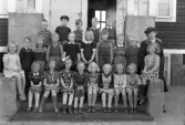 Foto av en skolklass med lärarinna, som samlats på skolans yttertrappa.
