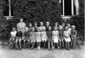 Foto av en skolklass med lärarinna, som samlats utanför skolan.