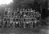 Foto av en grupp flickor i baddräkt.
Simskola (?).