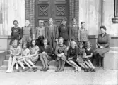 Foto av en skolklass med lärarinna, som samlats utanför skolans port.