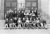 Foto av en skolklass med lärarinna, som samlats utanför skolans port.