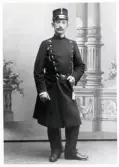 Poliskonstapel Carl Wilhelm Liljegren, Växjö, i full uniform.
Observera visselpipan till vänster på rocken.
Helfigur, en face. Ateljéfoto.