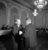 Sammanträde på Stadshotellet, 1943. 
Ett överlämnande av något mellan två medelålders herrar i kostym.