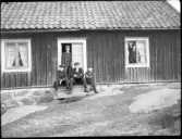 Fem pojkar vid Drängstugan i Stensjö by. I dörren står Eugén Stensiö, poserande i fönstret är Bengt Stensiö, och pojken till höger på trappan är Erik Karlsson.