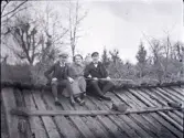 Bengt Stensiö, Ingrid Erlandsson och en till pojke med gevär på ett vedtak till ett uthus i Stensjö by. I bakgruden syns flera hamlade träd.