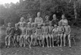 Foto av en grupp pojkar, klädda i badbyxor m.m.
Simskola (?)