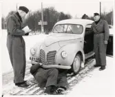 Konstaplarna Bengt Skoog och Harald Steen undersöker en bil på en vinterväg, tillsammans med överkonstapel Gösta W. Axelsson.
Bild och reportage i 