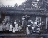 Gruppbild vid stuga med vasstak