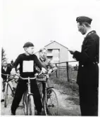 Poliskonstapel  Lennart Baugert har trafikundervisning med några skolpojkar. Alvesta 1956.