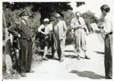 Överkonstapel Gösta W Axelsson (i kostym och hatt) och konstapel Uno Logarn (i golfbyxor) vid en syning längs en grusväg, 1949.