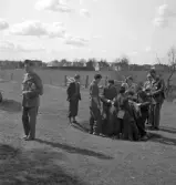 När våren kom, 1944. 
En övning i orientering, strax utanför Växjö. Några barn har samlats
kring en stubbe, övervakade av sin fröken och några män i uniform. 
I bakgrunden syns en åker och några bostadshus.