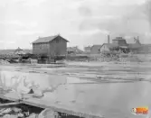 Till vänster bostäder på Holmen, Strandmagasinbyggnaden och masugnen till höger, Ljusne.