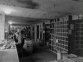 Några män arbetar i Monarks centrallager i Rommelska fastighetens gårdshus. Cirka 1935. Mannen närmast kameran är John Hansson. (Se även bild GB1_978)
