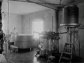 Interiör från mejeri, Varberg. En kvinna och arbetar vid ett kar.