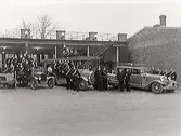 Varbergs brandkår. Brandsoldaterna poserar med tre brandbilar framför vagnhallen på brandstationen, Engelbrektsgatan 5.