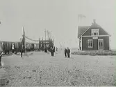 Rolfstorps järnvägsstation vid invigningen av Varberg-Ätrans järnväg april 1911. Ett tåg står inne vid stationen och personer finns vid tåget och på den utsmyckade perrongen.