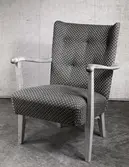 Stoppad Triva Byggfåtölj med armlän och ben av trä, på varuhuset Nordiska Kompaniet 1945. Serien Triva Bygg var Sveriges första monteringsbara möbler som levererades i platt paket, komplett med skruvar och beslag.