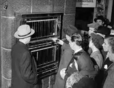 Folksamling vid cigarettautomat, Nordiska Kompaniet.