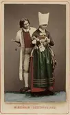 Dräktdockor med huvuden skulpterade av C A Söderman, troligen visade på världsutställningen i Wien 1873. Man och kvinna i dräkter från Vingåker, Södermanland. Handkolorerat fotografi efter förlaga från målning av J W Wallander.