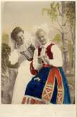 Ett handkolorerat foto på två kvinnor klädda i folkdräkt från Skåne eller Småland.