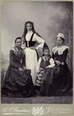 Grupporträtt med tre unga damer och en liten flicka klädda i folkdräkt poserar.