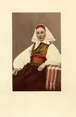 Ingeborg från Färnäs, Mora, klädd i folkdräkt från Dalarna. Handkolorerat porträttfoto.