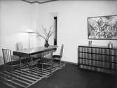 Interiör, fyra stålstolar och bord med en vas med kvistar. Ett sideboard med två tennvaser. Tavla på väggen. Möbelutställningen 1929. 