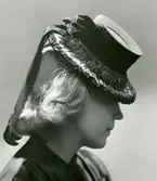 Porträtt av en kvinna i stråhatt med band i filt.