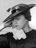 Kvinnlig modell i hatt från Madame Le Monnier. Dekorband i lack.  Nordiska Kompaniet, Stockholm.